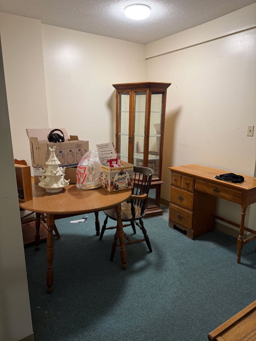 Empty room with a wooden table, chair, storage boxes, and a glass display cabinet.