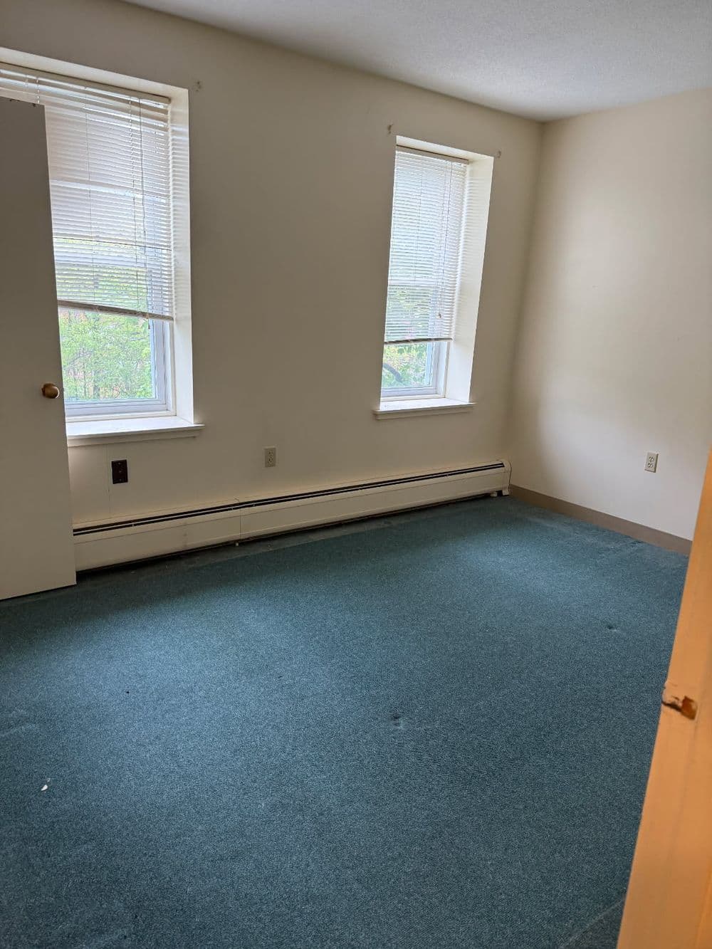 Cozy living room with floral couches, wooden table, and beige armchairs on green carpet.