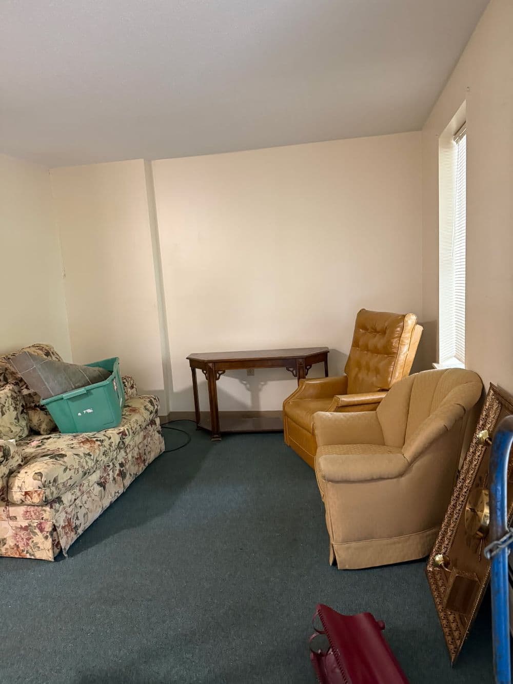 Cozy living room featuring floral sofa, two armchairs, and a wooden table on green carpet.